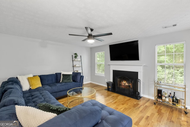 living room with ceiling fan, plenty of natural light, a textured ceiling, and hardwood / wood-style flooring