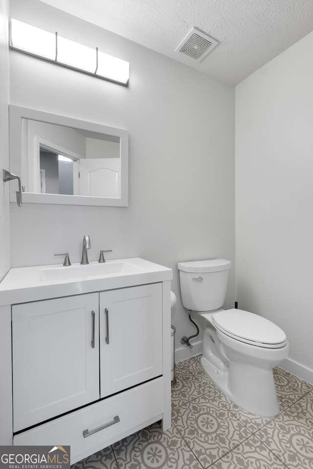 bathroom featuring vanity, a textured ceiling, toilet, and tile patterned flooring