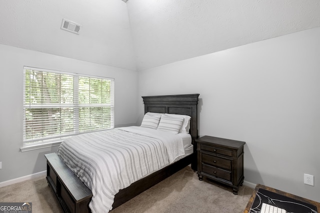 bedroom with vaulted ceiling, light carpet, and multiple windows