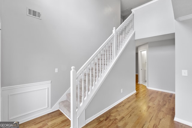 stairs featuring ornamental molding and hardwood / wood-style flooring