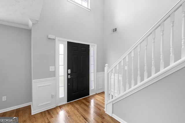 entrance foyer featuring hardwood / wood-style flooring, ornamental molding, and a textured ceiling