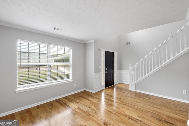 entrance foyer with a textured ceiling, hardwood / wood-style flooring, and crown molding