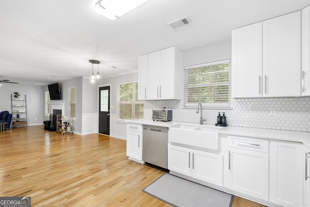 kitchen with white cabinetry, dishwasher, sink, light hardwood / wood-style flooring, and pendant lighting