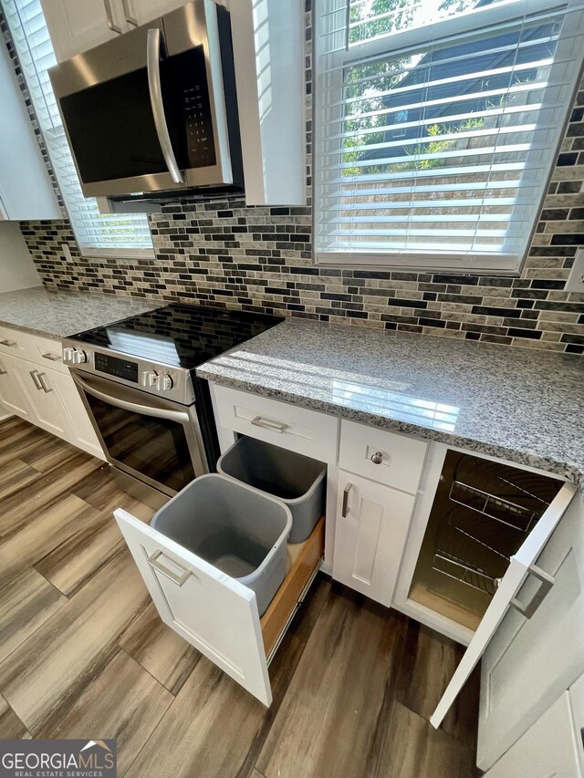 kitchen with decorative backsplash, white cabinetry, light stone countertops, and appliances with stainless steel finishes