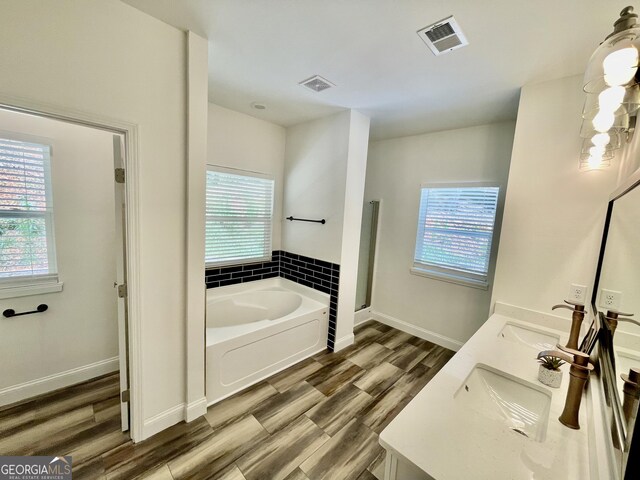 bathroom featuring plus walk in shower, wood-type flooring, and vanity