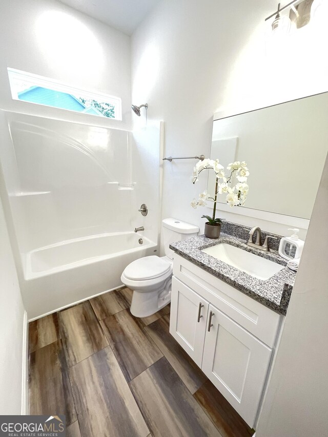 full bathroom featuring hardwood / wood-style floors, vanity, shower / bathtub combination, and toilet