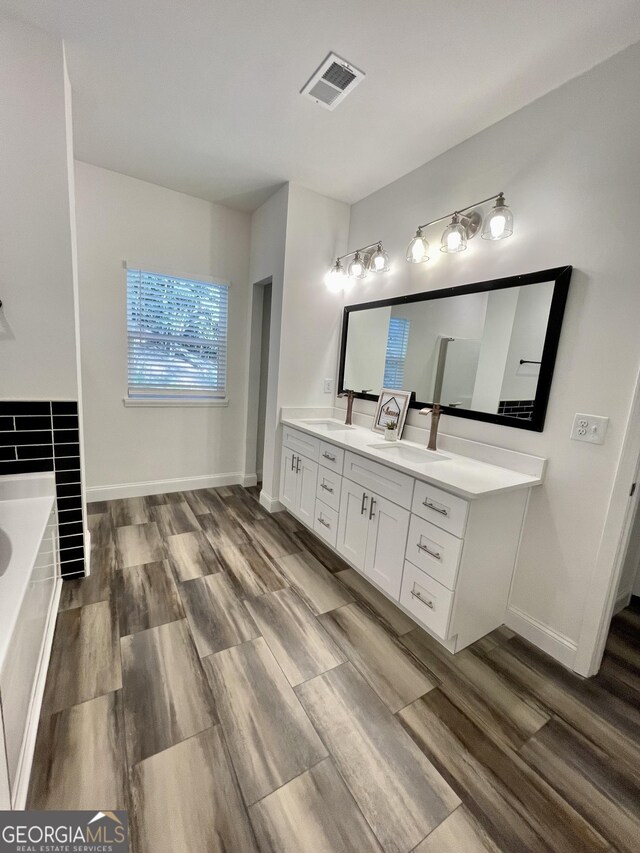 bathroom featuring hardwood / wood-style floors, vanity, and a bath