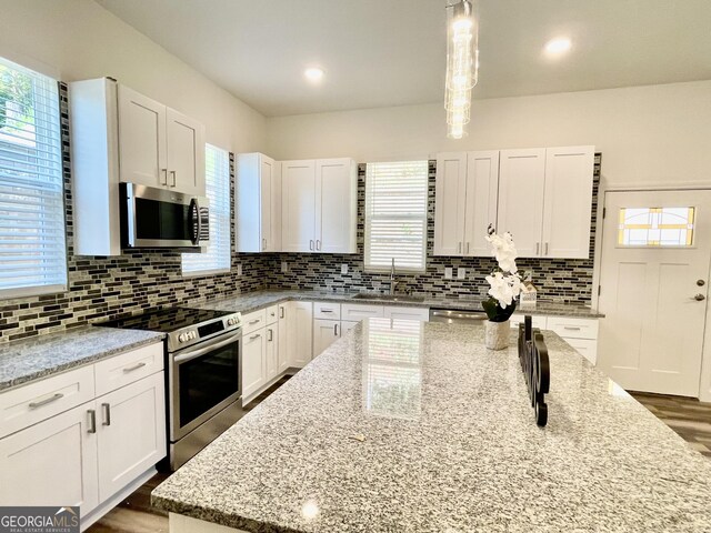 kitchen featuring white cabinetry, light stone countertops, decorative light fixtures, and appliances with stainless steel finishes