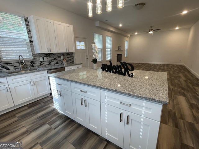 kitchen with pendant lighting, ceiling fan, a kitchen island, and white cabinetry