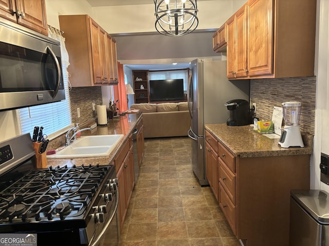 kitchen with tasteful backsplash, stainless steel appliances, decorative light fixtures, and sink