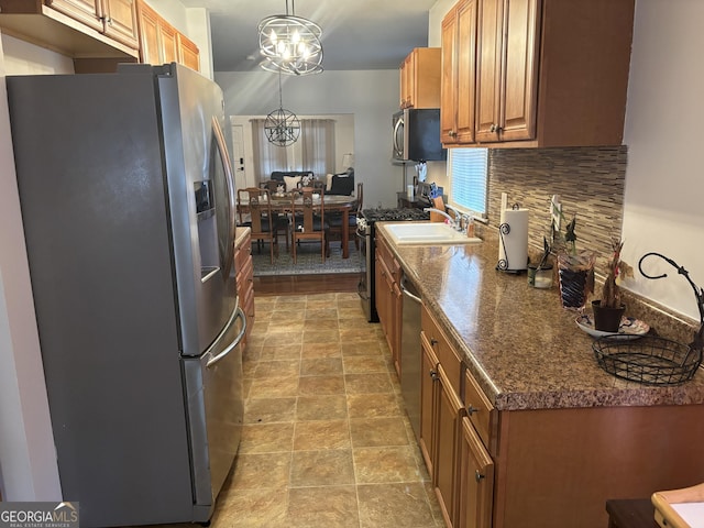 kitchen featuring backsplash, stainless steel appliances, decorative light fixtures, dark stone counters, and a chandelier