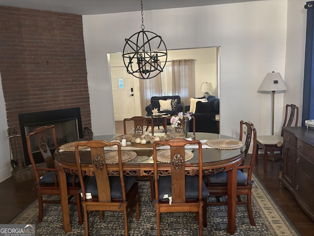 dining space featuring a fireplace, hardwood / wood-style floors, and a notable chandelier