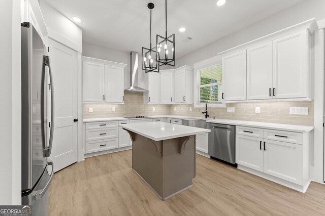 kitchen with white cabinets, stainless steel appliances, wall chimney range hood, and a kitchen island