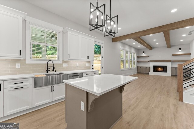 kitchen featuring a kitchen bar, sink, pendant lighting, white cabinets, and a kitchen island