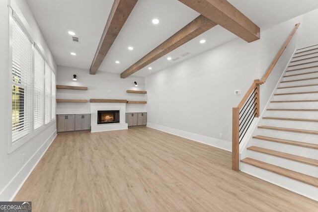 unfurnished living room featuring beam ceiling and light wood-type flooring