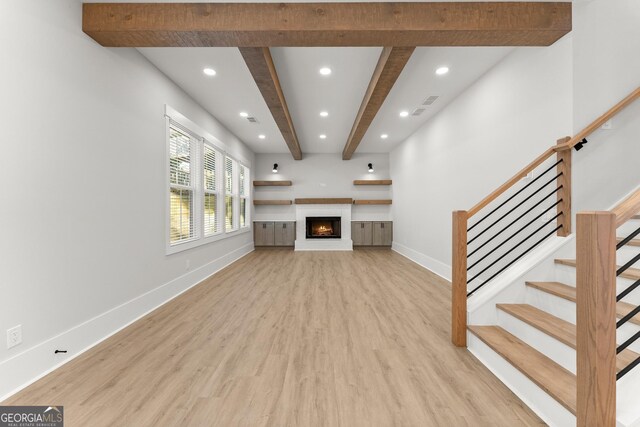 unfurnished living room featuring beamed ceiling and light hardwood / wood-style flooring