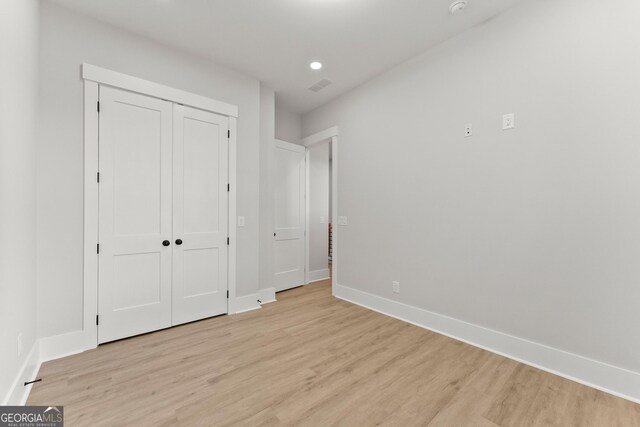 unfurnished bedroom featuring light wood-type flooring and a closet