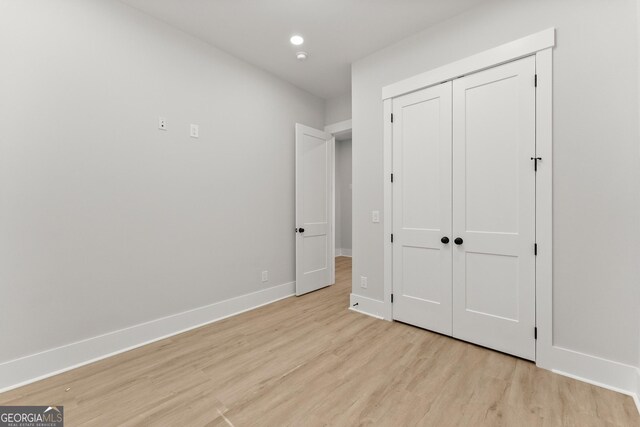 unfurnished bedroom featuring light wood-type flooring and a closet