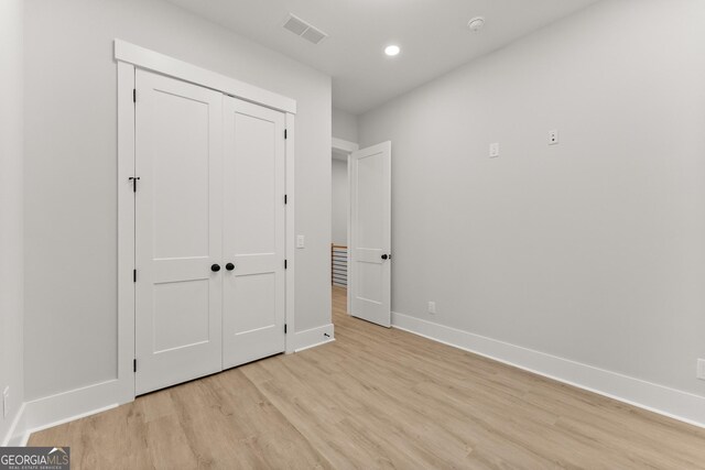 unfurnished bedroom with a closet and light hardwood / wood-style flooring