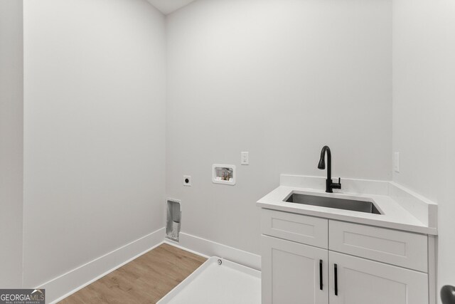 laundry room featuring cabinets, washer hookup, electric dryer hookup, sink, and light hardwood / wood-style flooring