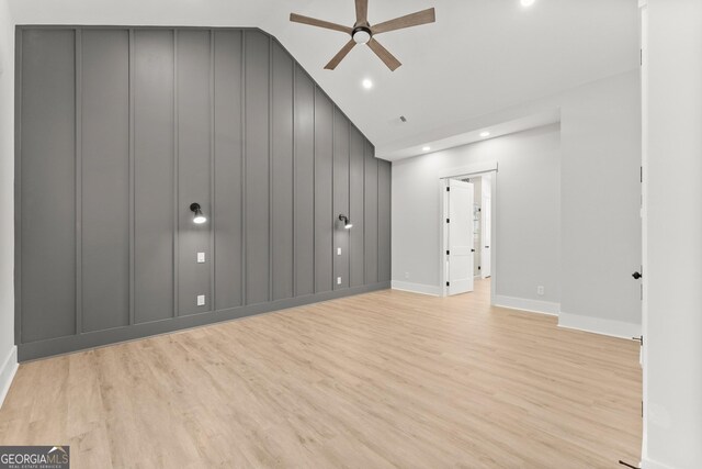 spare room with ceiling fan, lofted ceiling, and light wood-type flooring