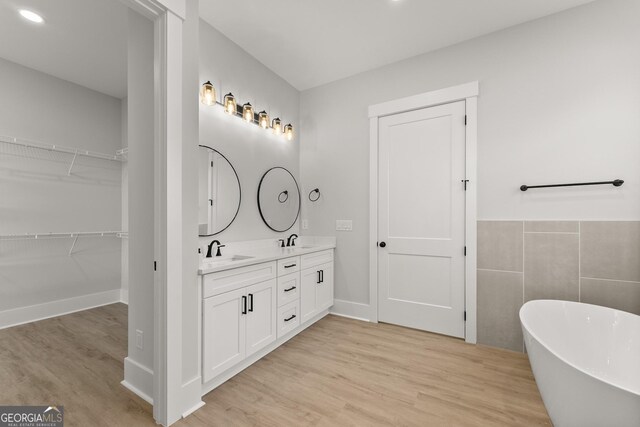 bathroom featuring hardwood / wood-style floors, vanity, and a tub to relax in