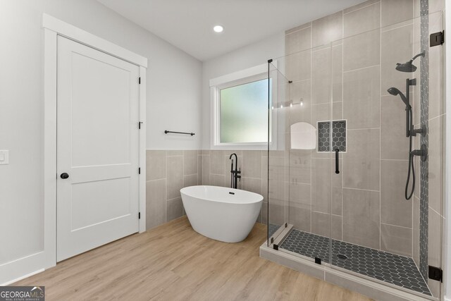 bathroom featuring hardwood / wood-style flooring, tile walls, and independent shower and bath