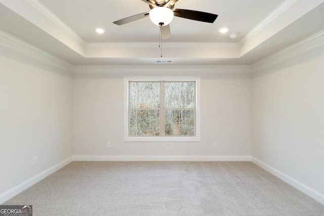 carpeted spare room with a tray ceiling, ornamental molding, and ceiling fan