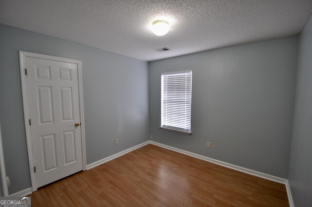 unfurnished room with hardwood / wood-style floors and a textured ceiling