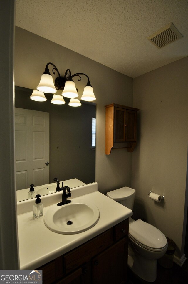 bathroom featuring vanity, toilet, and a textured ceiling