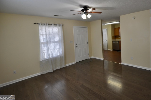 empty room with a textured ceiling, ceiling fan, and dark wood-type flooring