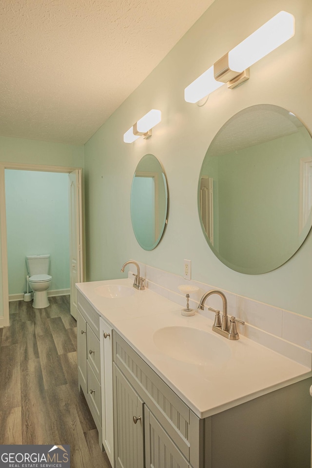 bathroom with vanity, a textured ceiling, hardwood / wood-style flooring, and toilet