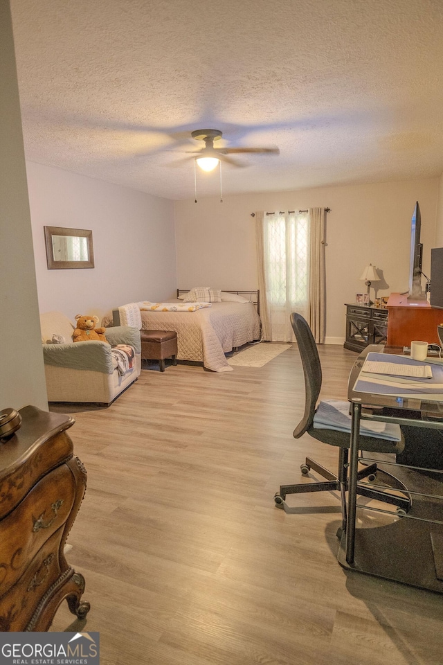 bedroom featuring ceiling fan, a textured ceiling, and light hardwood / wood-style flooring