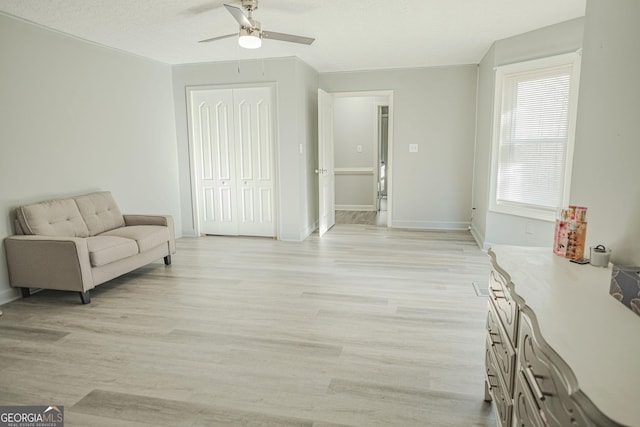 living area featuring a textured ceiling, light hardwood / wood-style flooring, and ceiling fan