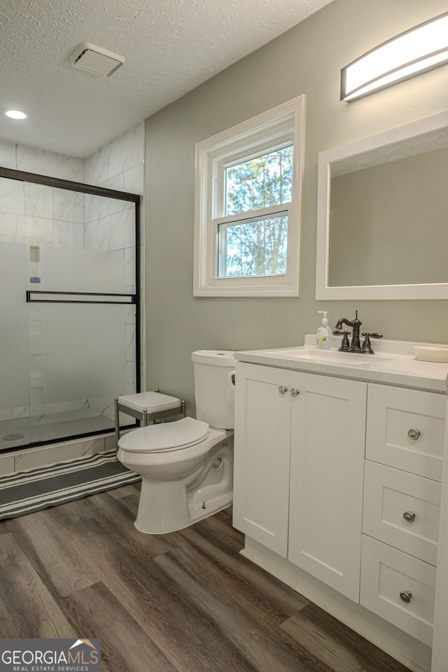 bathroom featuring wood-type flooring, a shower with shower door, and a textured ceiling