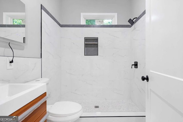 bathroom featuring vanity, a healthy amount of sunlight, toilet, and tile walls