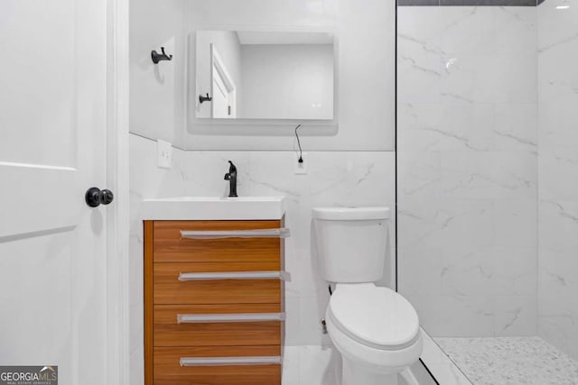 bathroom featuring walk in shower, vanity, toilet, and tile walls