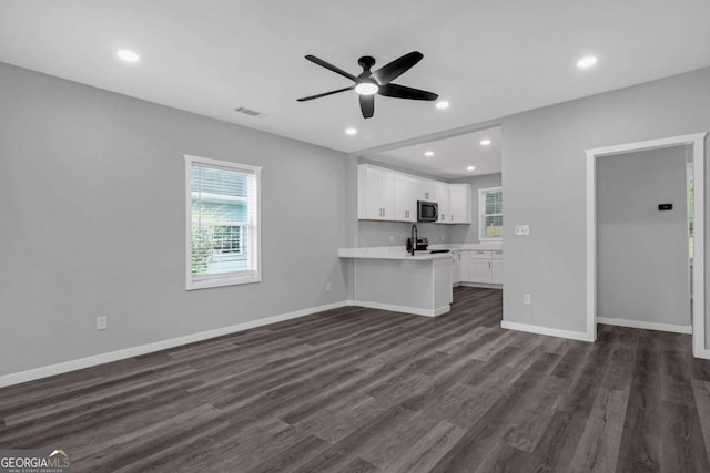 unfurnished living room featuring a wealth of natural light, ceiling fan, and dark hardwood / wood-style floors