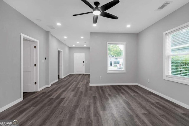 unfurnished living room featuring ceiling fan, a healthy amount of sunlight, and dark wood-type flooring