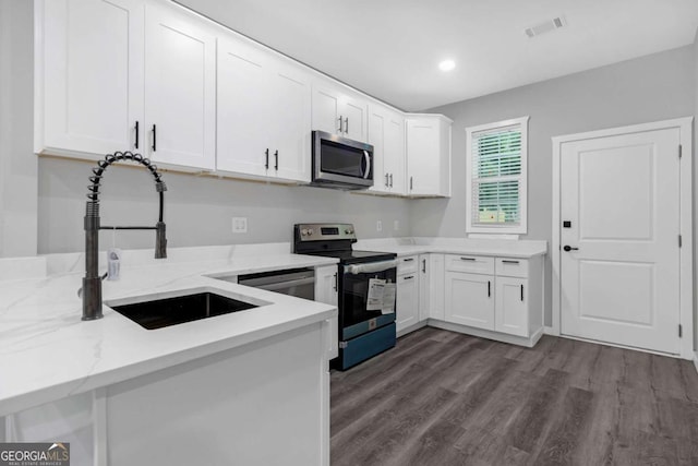 kitchen with appliances with stainless steel finishes, light stone counters, sink, hardwood / wood-style floors, and white cabinetry