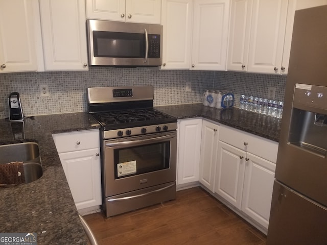 kitchen with dark stone countertops, white cabinets, dark wood-type flooring, and appliances with stainless steel finishes