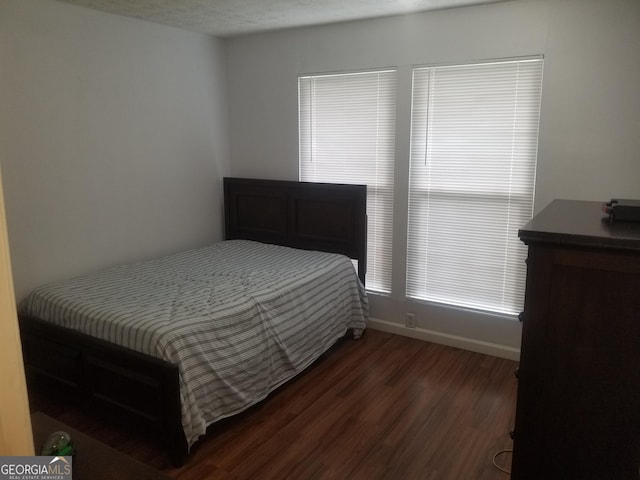 bedroom featuring dark wood-style floors and baseboards