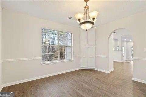 spare room with an inviting chandelier and dark wood-type flooring