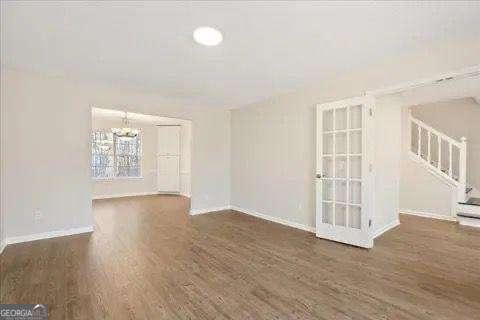 empty room with dark hardwood / wood-style flooring and a notable chandelier