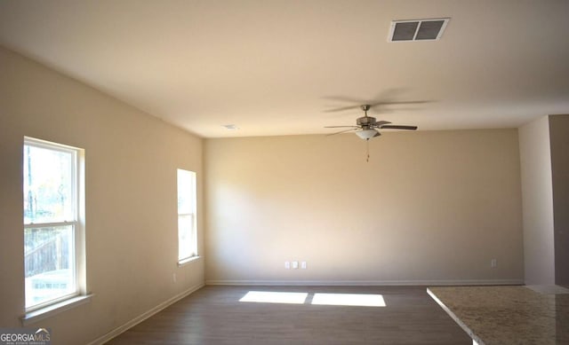 spare room with dark hardwood / wood-style floors, a wealth of natural light, and ceiling fan