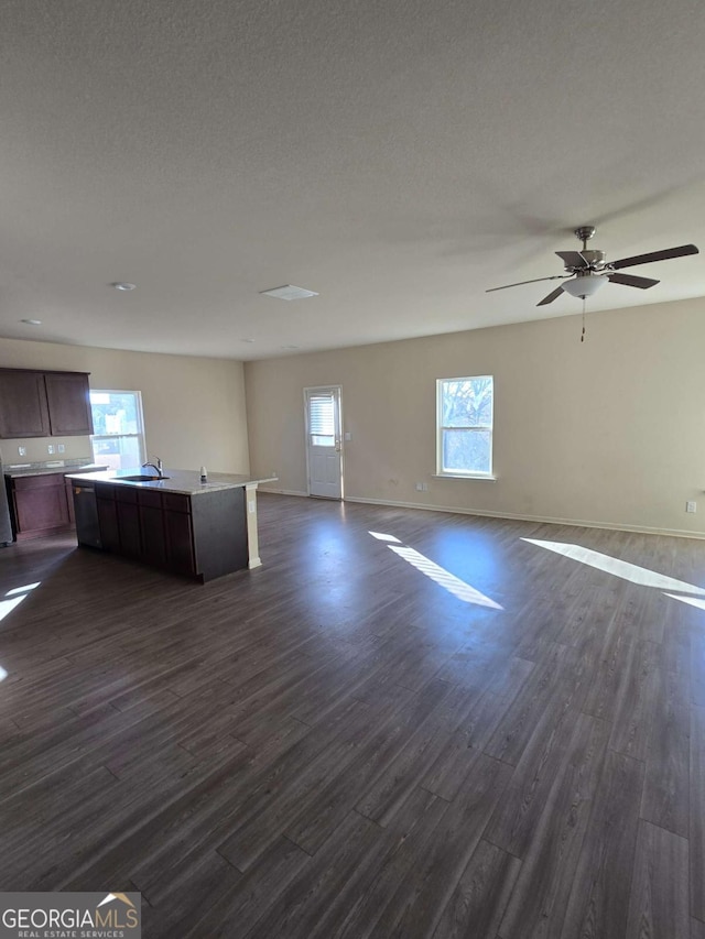 unfurnished living room with a wealth of natural light, sink, ceiling fan, and dark wood-type flooring