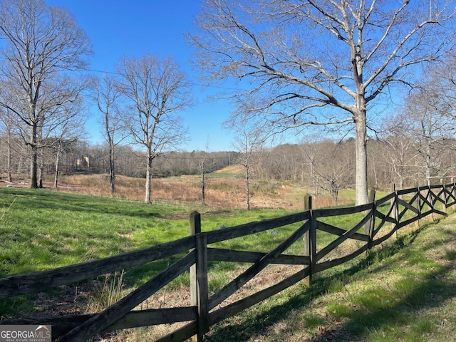 view of gate with a lawn and a rural view