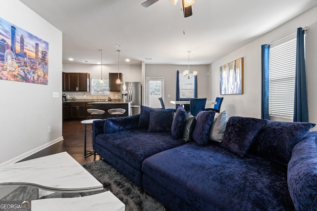 living room with dark hardwood / wood-style floors, plenty of natural light, and ceiling fan with notable chandelier