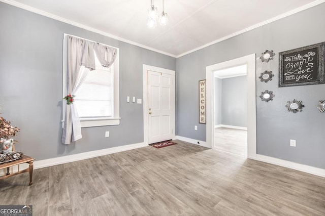 entryway with hardwood / wood-style floors, an inviting chandelier, and ornamental molding