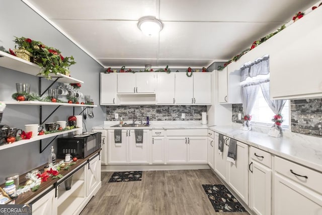 kitchen with white cabinets, light wood-type flooring, tasteful backsplash, and sink